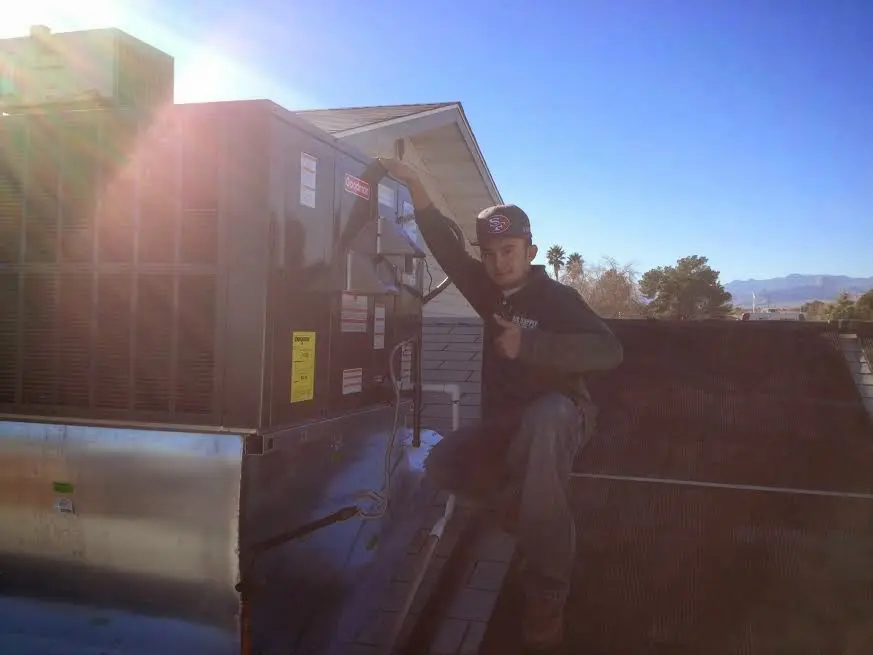 HVAC technician performing Air Duct Cleaning on a rooftop unit in The Woodlands